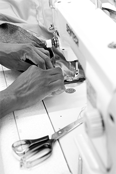 Grey scale workers hands sewing fabric